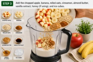 Adding chopped apple, banana, rolled oats, cinnamon, almond butter, vanilla extract, honey, and ice cubes to a blender for Apple Cinnamon Smoothie Recipe.