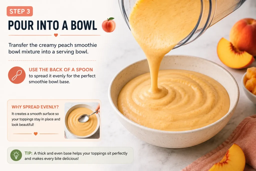 Pouring a thick and creamy peach smoothie bowl mixture from a blender into a serving bowl and smoothing the surface with a spoon.